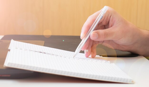 Mains d'homme d'affaires avec un cahier d'écriture de stylo sur la table de bureau se bouchent. Concept d'entreprise.