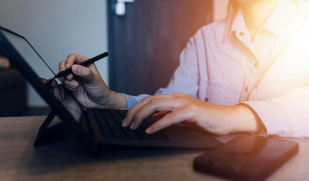 Mains d'homme d'affaires travaillant avec les finances sur le coût et la calculatrice et l'ordinateur portable avec tablette smartphone au bureau à la lumière du matin