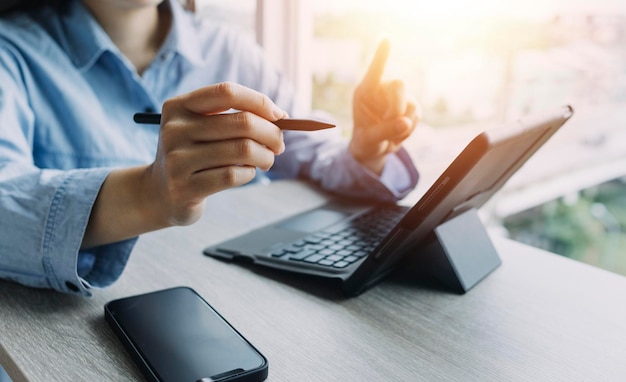 Mains d'homme d'affaires travaillant avec les finances sur le coût et la calculatrice et l'ordinateur portable avec tablette smartphone au bureau à la lumière du matin