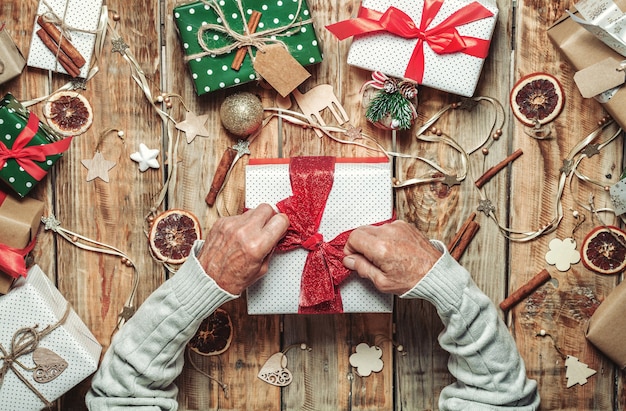 Les mains de l'homme âgé âgé d'emballage des cadeaux de Noël sur la table