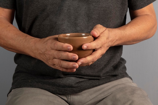 Mains d'un homme âgé tenant une tasse avec une boisson chaude