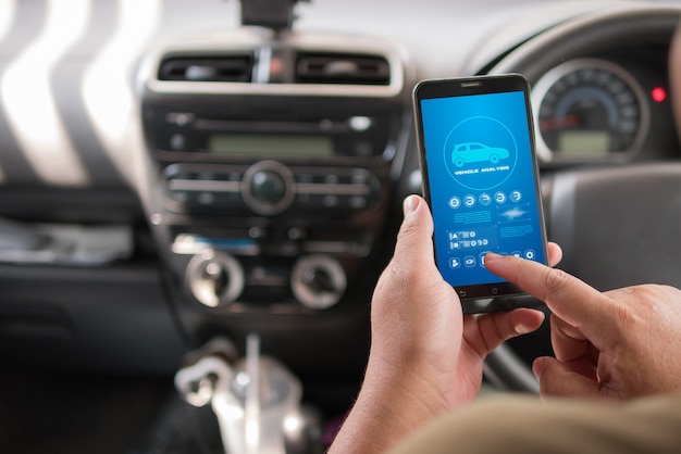 Mains d&#39;homme à l&#39;aide de l&#39;application d&#39;analyse de véhicule de téléphone intelligent mobile dans la voiture