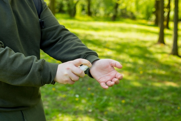 Les mains de l'homme à l'aide d'un désinfectant pour les mains, contre le nouveau coronavirus ou la maladie à virus Corona sur un parc public de la ville. Concept antiseptique, hygiène et santé