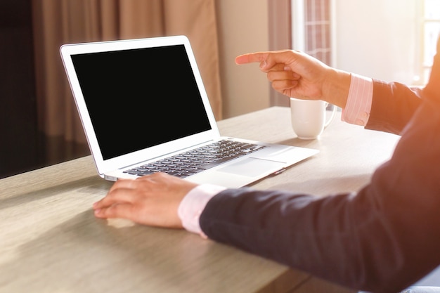 Les mains de l&#39;homme à l&#39;aide d&#39;un ordinateur portable avec écran blanc sur un bureau à l&#39;intérieur de la maison.