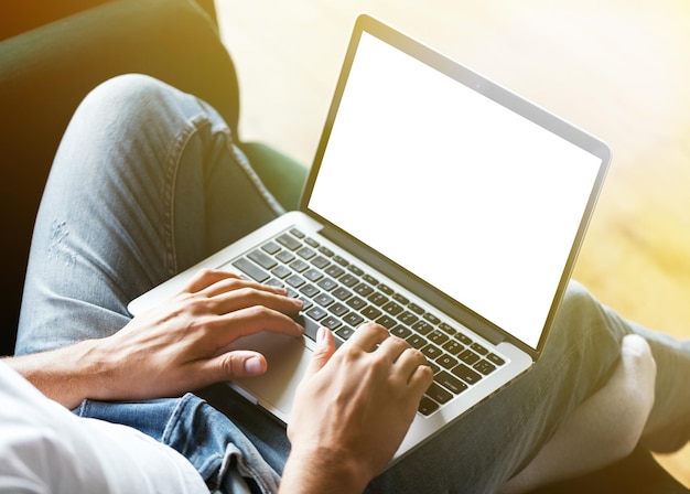 Mains de l'homme à l'aide d'un ordinateur portable avec écran vide sur le bureau à l'intérieur de la maison Concept de travail