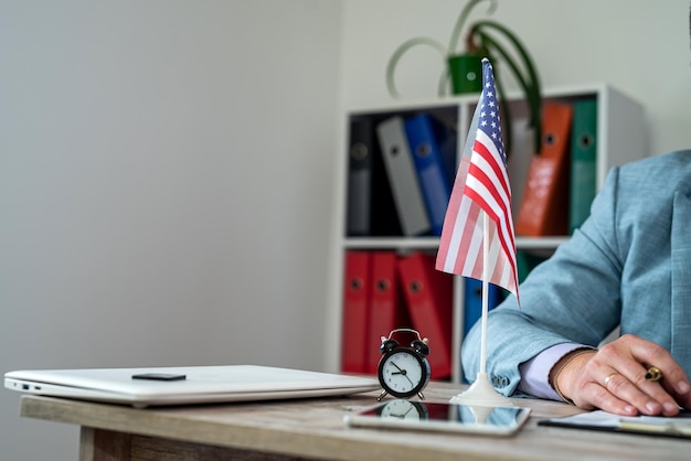 les mains d'un homme en costume derrière une table avec un drapeau américain sur elle style d'affaires affaires