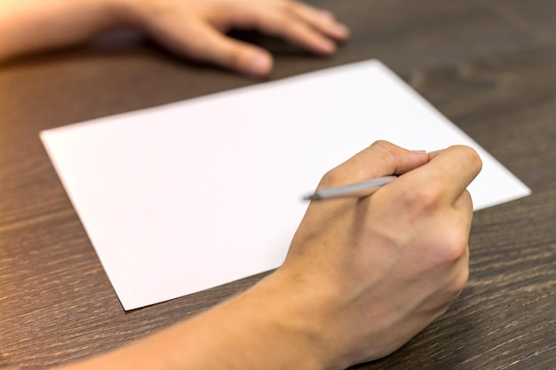 Photo des mains d'homme coupées par un papier blanc sur la table.