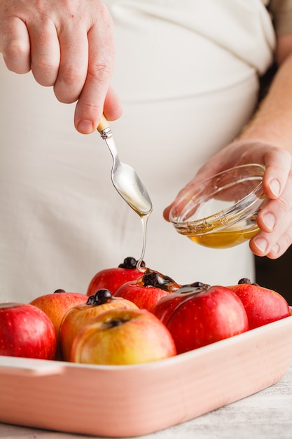 Mains d'homme avec du miel sur une pomme fraîche prête à cuire