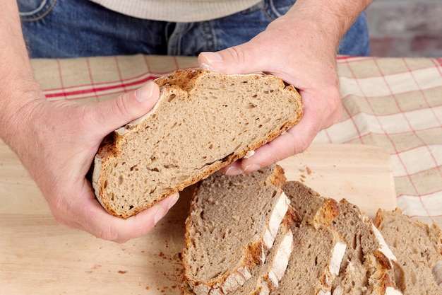 Mains d'homme avec du pain frais sur une table en bois