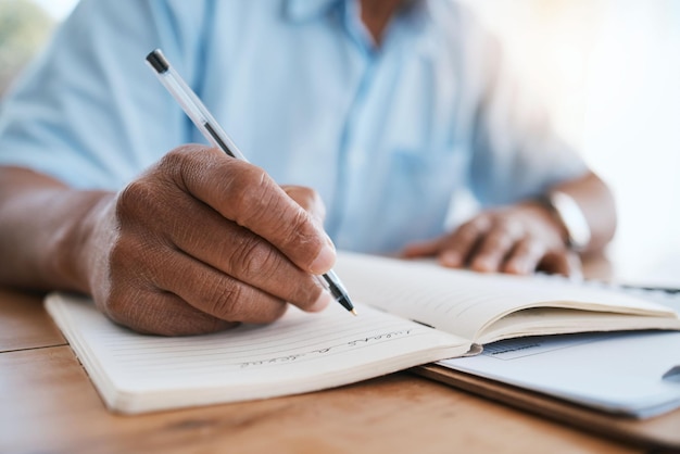 Mains d'homme et écriture dans un livre pour le budget des finances ou la planification du calendrier dans le travail à distance à la maison