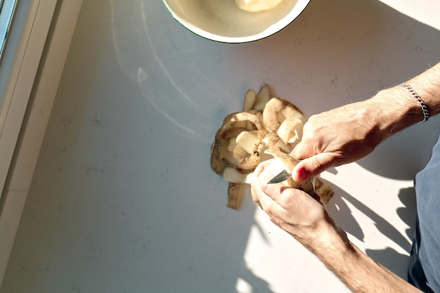 Mains d'un homme épluchant des pommes de terre, vue de dessus, avec espace de copie