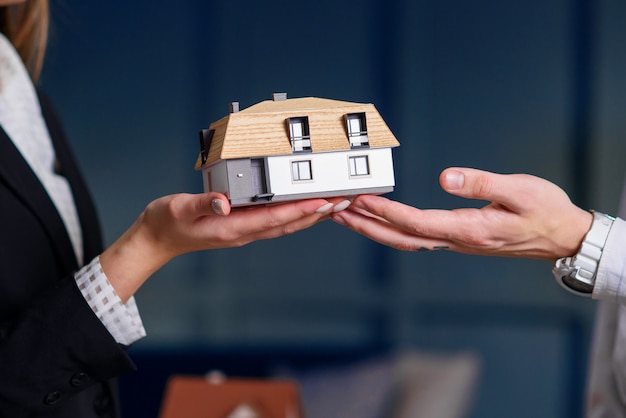 Mains d'homme et femme tenant le modèle 3d de maison.