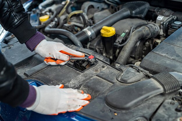 Les mains d'un homme fort en gants inspectent la voiture sous le capot pour déceler les dommages. Concept de réparation de voiture. Concept d'inspection de voiture.