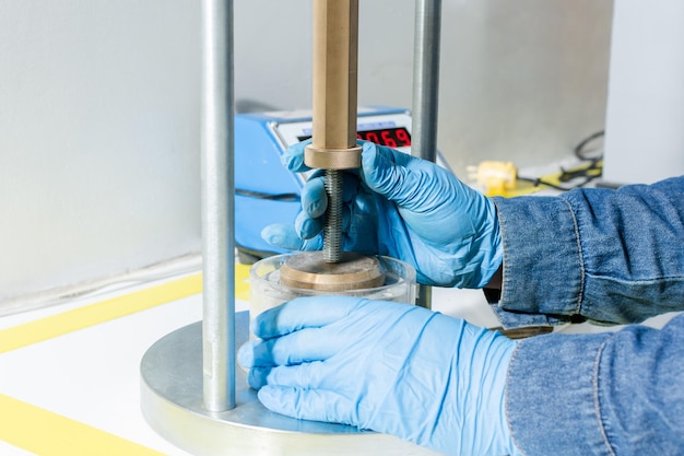 Mains d'homme industriel avec des gants en latex bleu à l'aide d'une machine de test de laboratoire de géologie