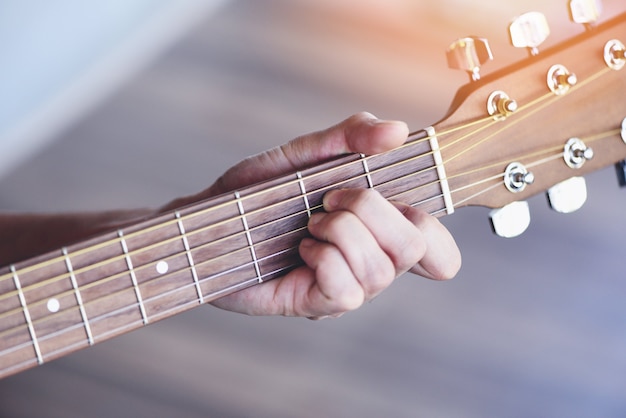 Mains de l'homme jouant de la guitare acoustique, gros plan joueur de guitare d'accord