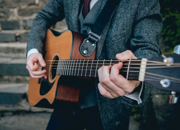 Mains d'homme jouant de la guitare acoustique