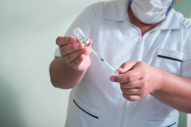 les mains d'un homme latin tenant une seringue et un liquide médicinal à injecter comme vaccin