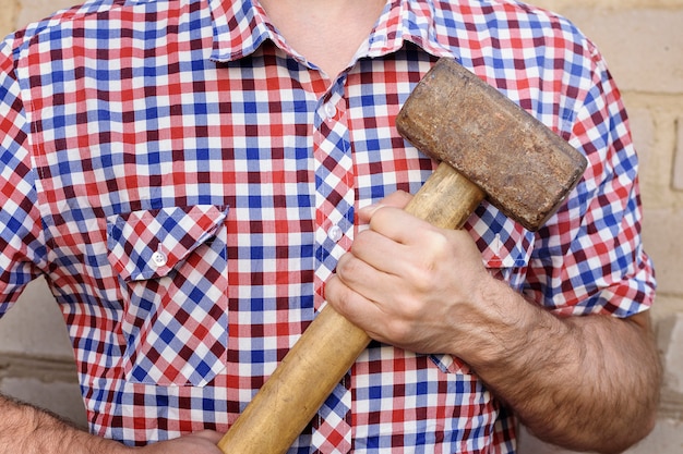 Mains d'homme avec un marteau, sur le mur de briques. Travail