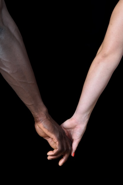 Photo une mains d'homme noir et femme blanche sur fond noir