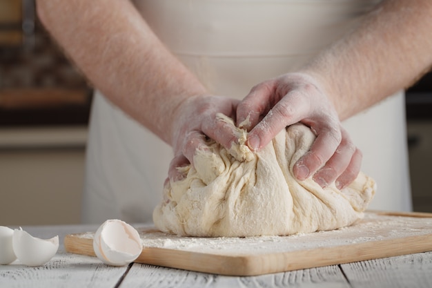 les mains de l'homme pétrir la pâte sur une table