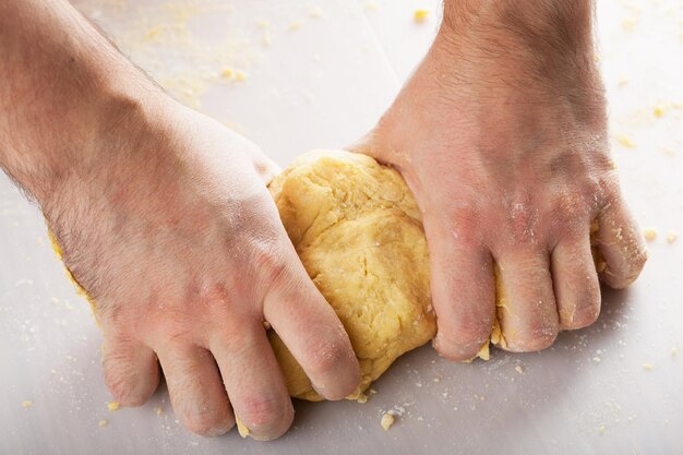 Photo mains d'homme pétrissant la pâte