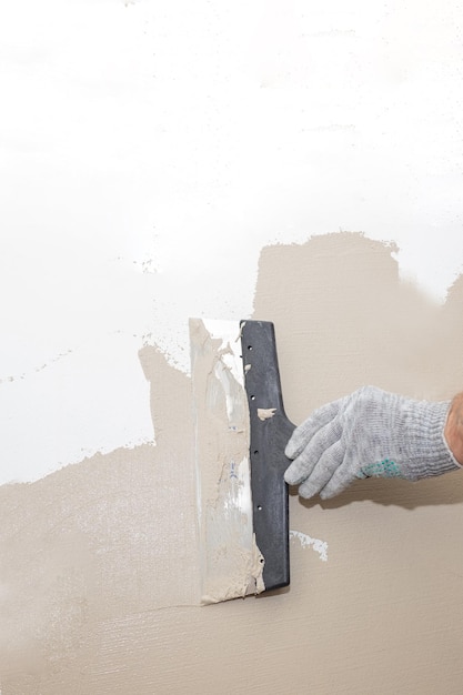 Mains homme plâtrier ouvrier du bâtiment au travail avec une truelle plâtrant un mur closeupConcept rénovation réparation révision contrat espace de copie de carreau