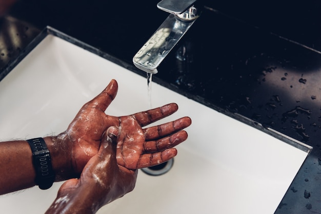 Les mains de l'homme se frottant avec du savon et de l'eau dans les éviers