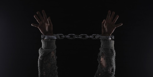 Les mains d'un homme sont tenues dans une chaîne.