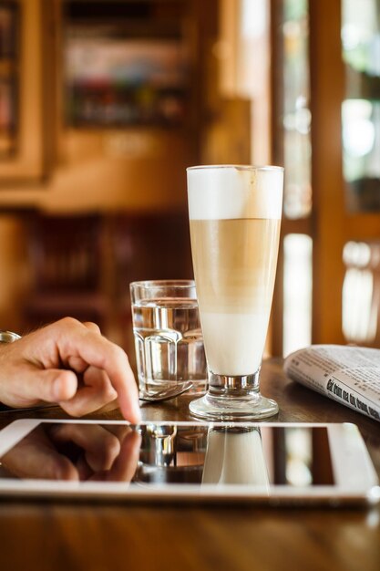 Photo mains d'un homme avec une tablette vierge sur une table d'espace de travail en bois