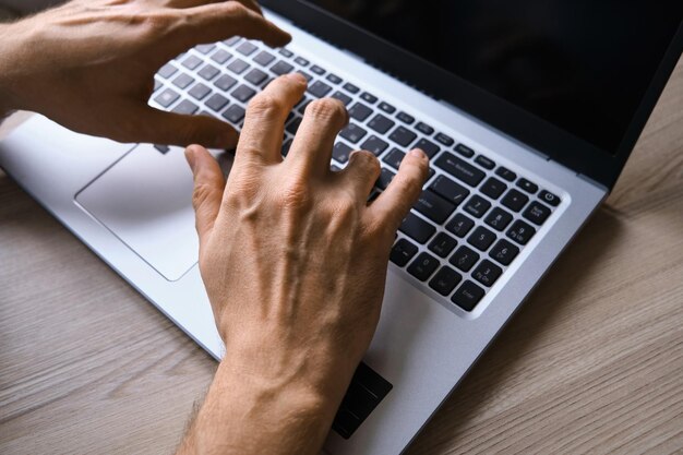 Les mains de l'homme tapant sur la vue de dessus du clavier d'ordinateur portable