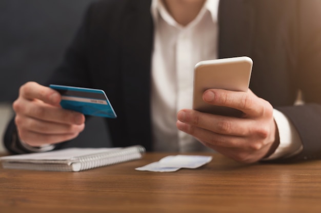 Les mains de l'homme tenant une carte de crédit et utilisant un smartphone pour faire des achats en ligne. Paiement en ligne, espace de copie