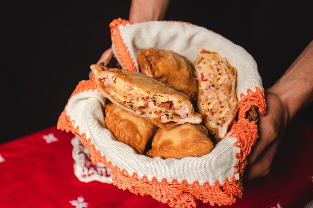 Mains d'un homme tenant un récipient avec des empanadas napolitaines.