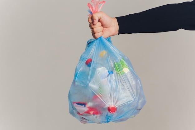 Mains d'homme tenant un sac poubelle isolé sur blanc