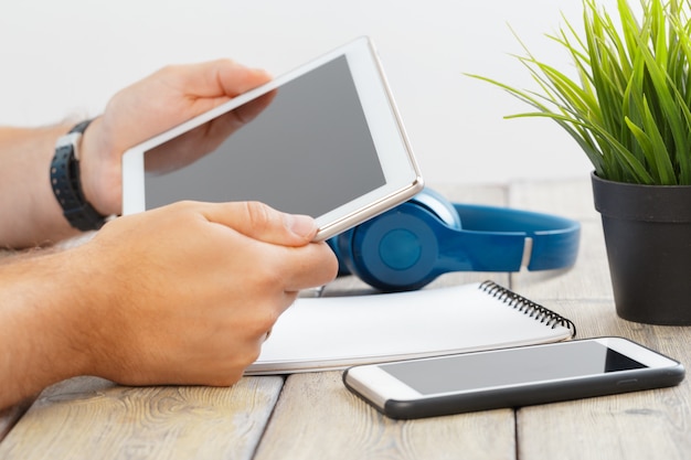 Mains d&#39;un homme tenant une tablette sur une table en bois