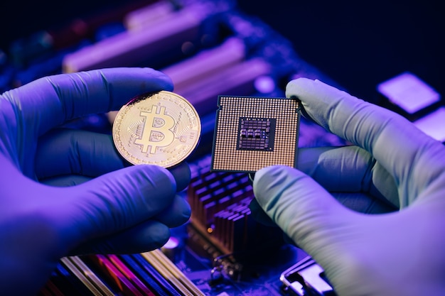 Les mains de l'homme tiennent Bitcoin or et cpu sur la carte mère