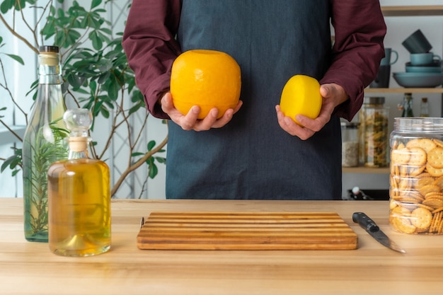 Les mains de l'homme tiennent le fromage hollandais entier Edam et le fromage de chèvre hollandais des Pays-Bas sur la cuisine