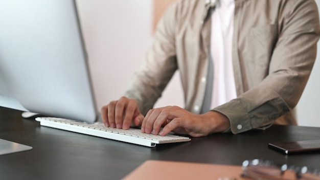 Mains d'homme de tir recadrée tapant sur un clavier sans fil