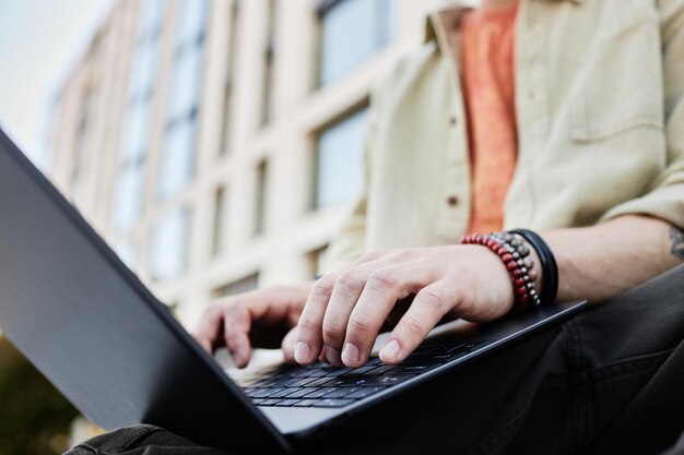 Mains d'homme en train de taper sur un ordinateur portable Travailler ou apprendre en ligne en plein air
