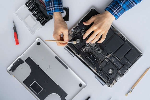 Les mains d'un homme travaillant dans le service informatique et enlevant la poussière de l'ordinateur portable personnel