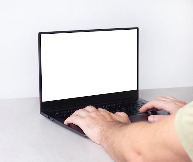 Mains d'un homme travaillant sur un ordinateur portable avec une maquette blanche sur l'écran