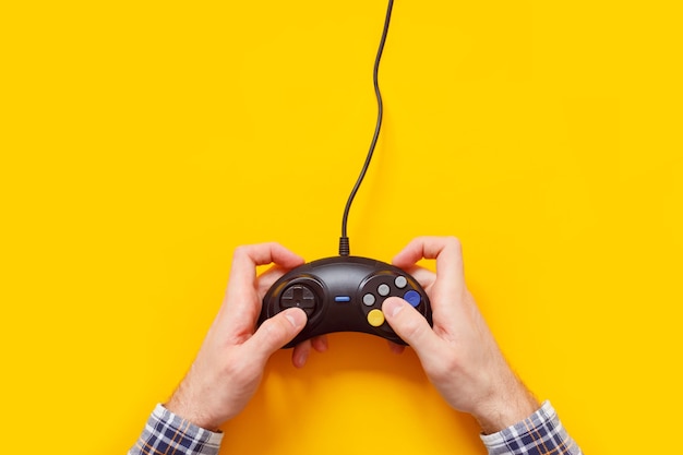 Photo les mains de l'homme avec une vieille manette de jeu filaire isolé sur jaune