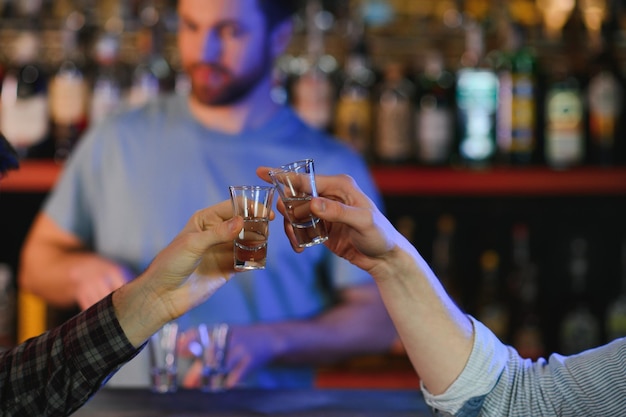 Les mains des hommes applaudissent avec des verres de vodka Les gens boivent à l'apéritif