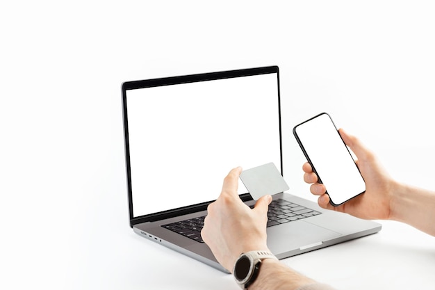 Mains d'hommes avec une carte et un téléphone sur le fond d'un ordinateur portable Paiement de livraison en ligne