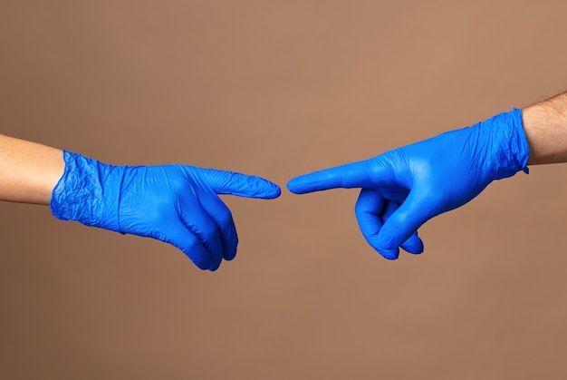 Photo les mains des hommes et des femmes dans des gants médicaux s'étirent l'une vers l'autre. concept d'aide. fermer