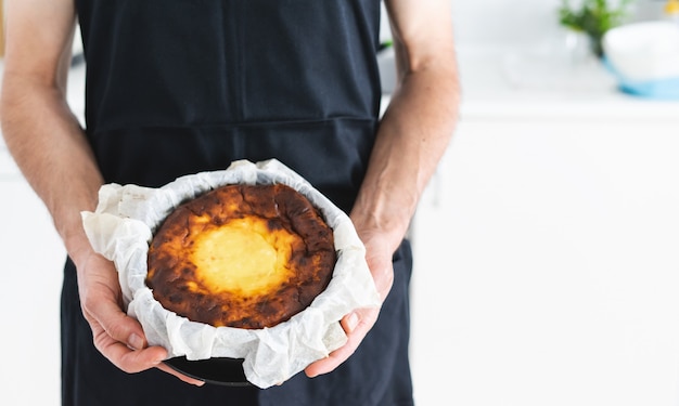 Les mains des hommes montrant un gâteau au fromage. Concept de cuisine.