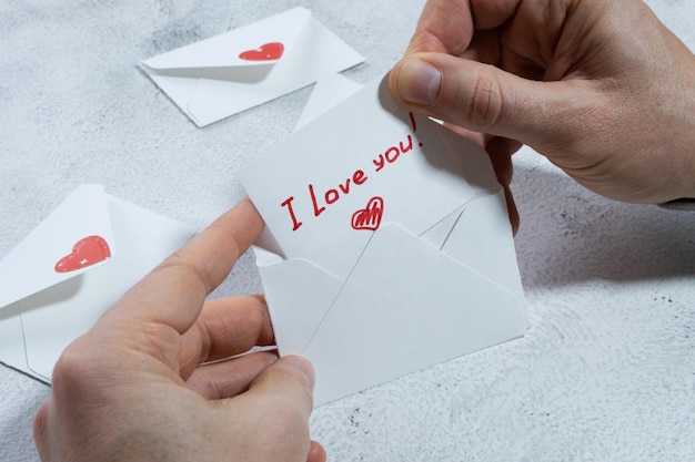 Les mains des hommes ouvrent une enveloppe blanche avec un coeur