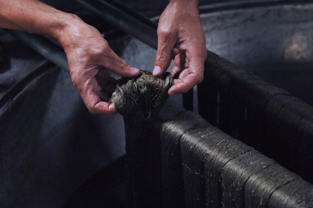 Les mains des hommes peignent les fils et les fils peignent le tissu dans l'auge