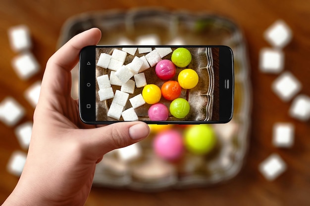 Les mains des hommes prennent la photographie de la nourriture sur la table avec le téléphone Bonbons et sucre