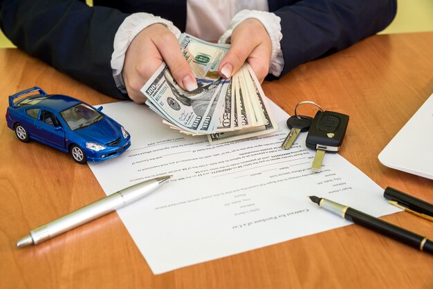 Les mains des hommes signant le formulaire de demande de contrat de voiture et la calculatrice, dollar, voiture