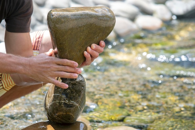 Des mains humaines construisent un cairn de pierres sur l'eau. équilibre et méditation